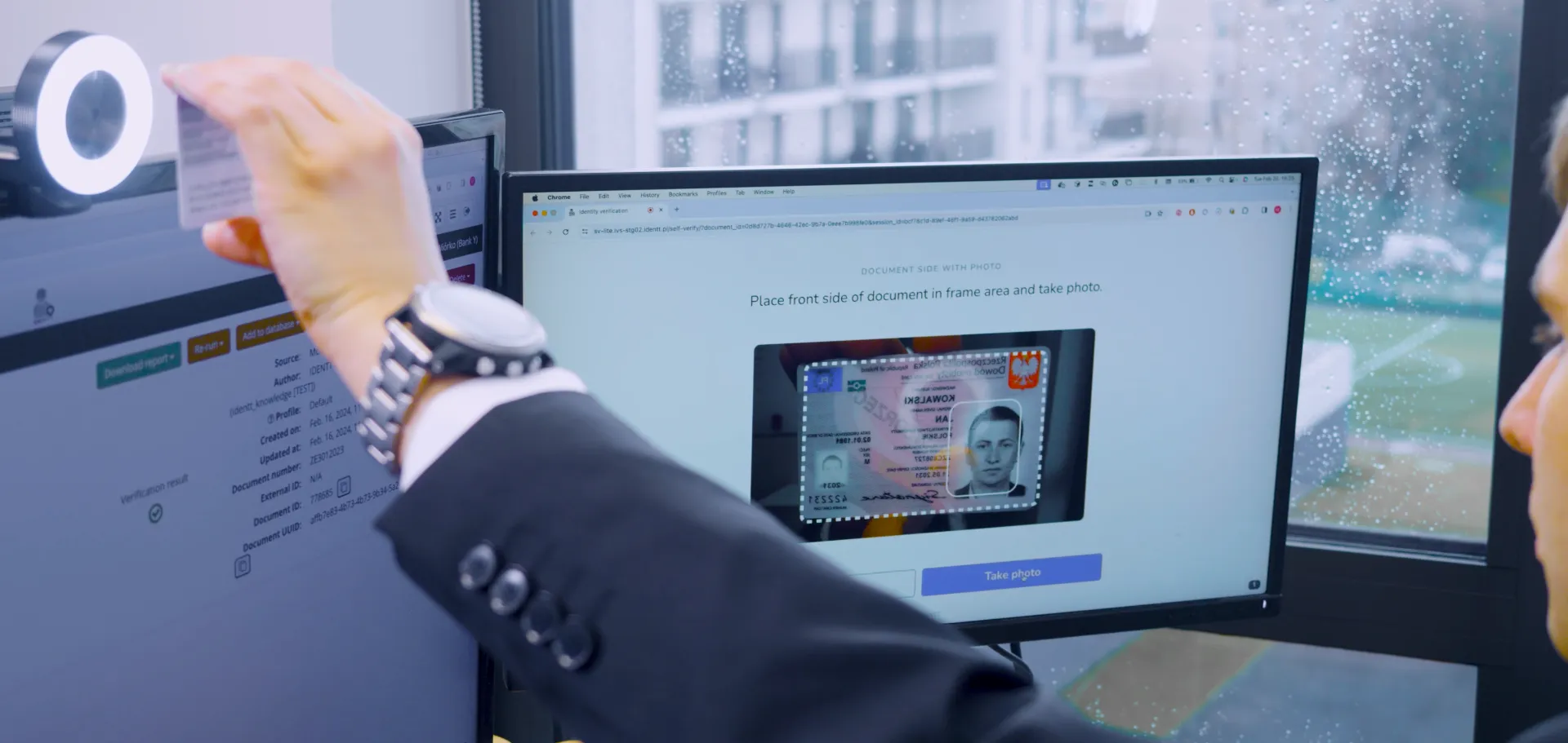 Male researcher holding specimen identity card up close to the web camera, with video feed shown on a rightmost computer screen via the IDENTT Self-Verify application